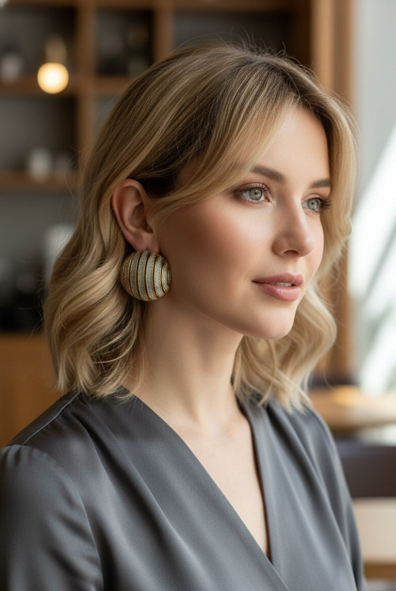 Close-up of a model wearing 80s inspired ribbed dome statement earrings in two-tone gold and silver textured design, perfect for retro luxury fashion.