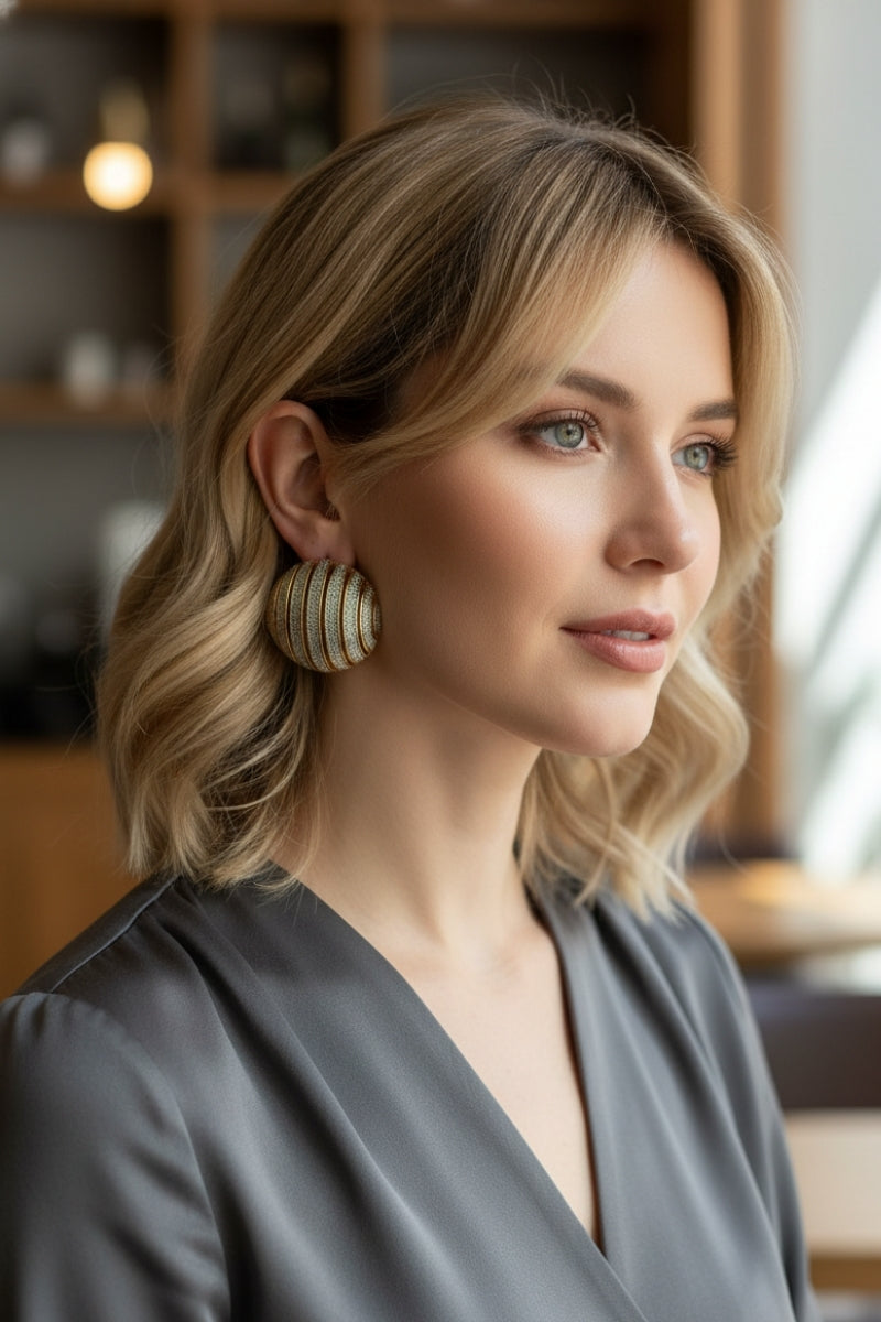 Close-up of a model wearing 80s inspired ribbed dome statement earrings in two-tone gold and silver textured design, perfect for retro luxury fashion.