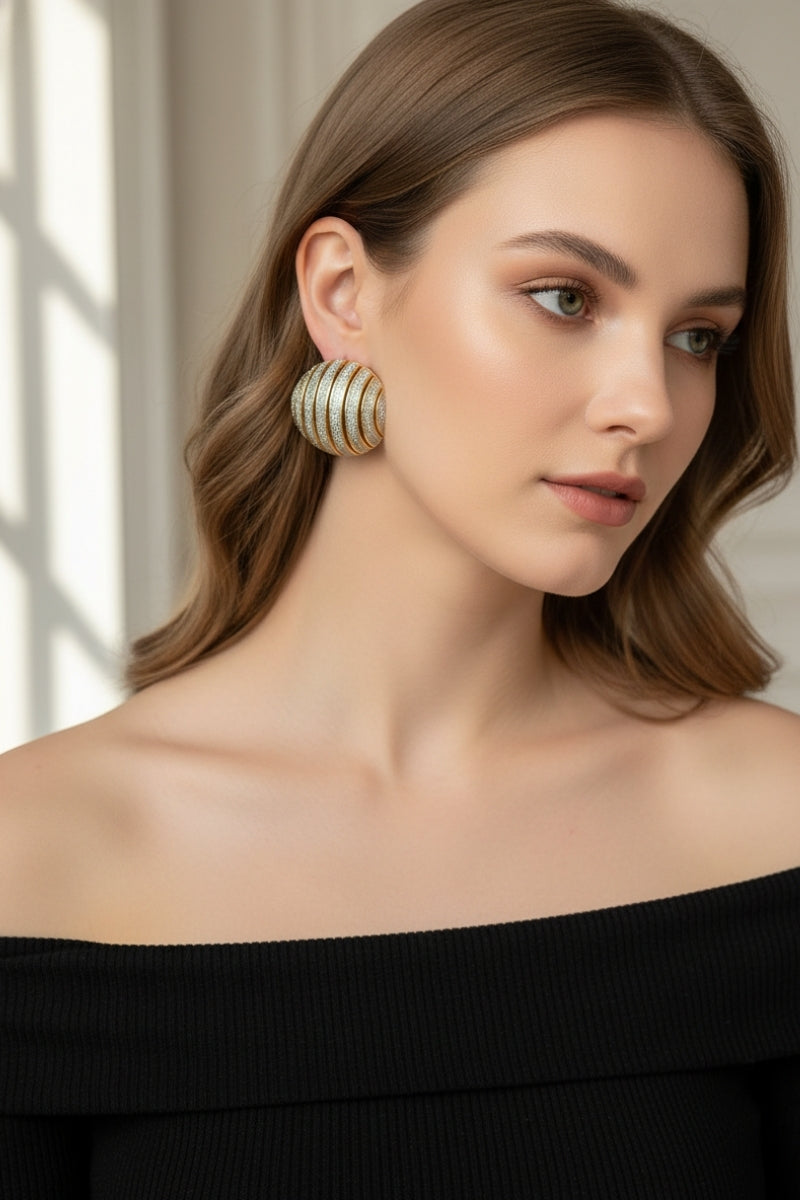 High-fashion portrait of a woman wearing sophisticated ribbed dome earrings in a gold and silver striped pattern, luxury accessory for formal events.