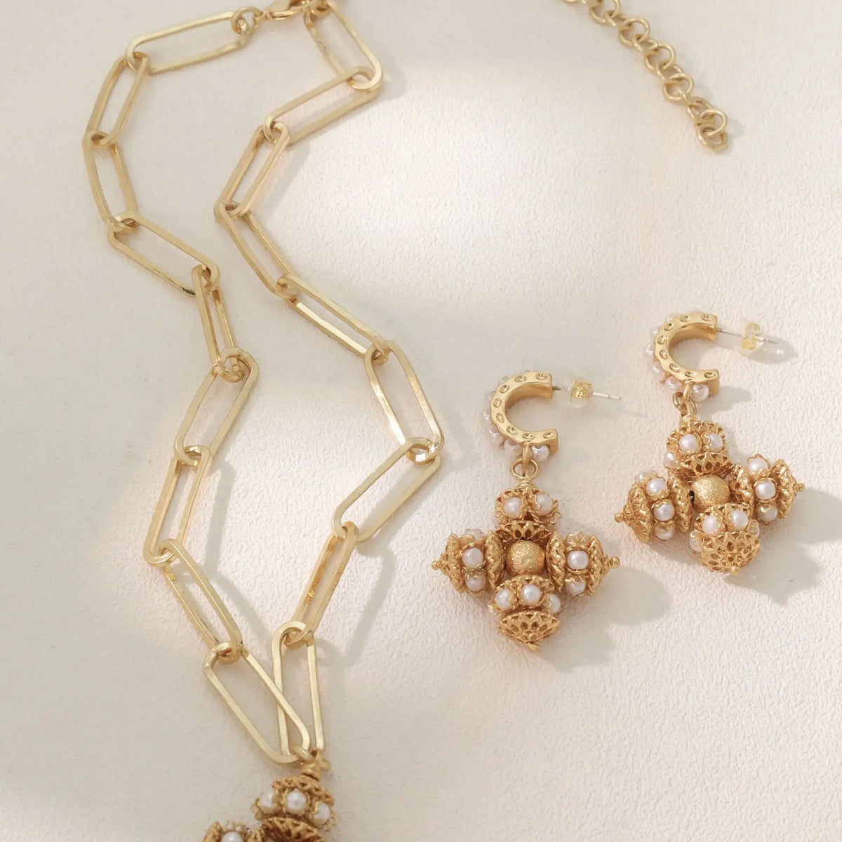 Opulence earrings styled beside a matching gold link necklace