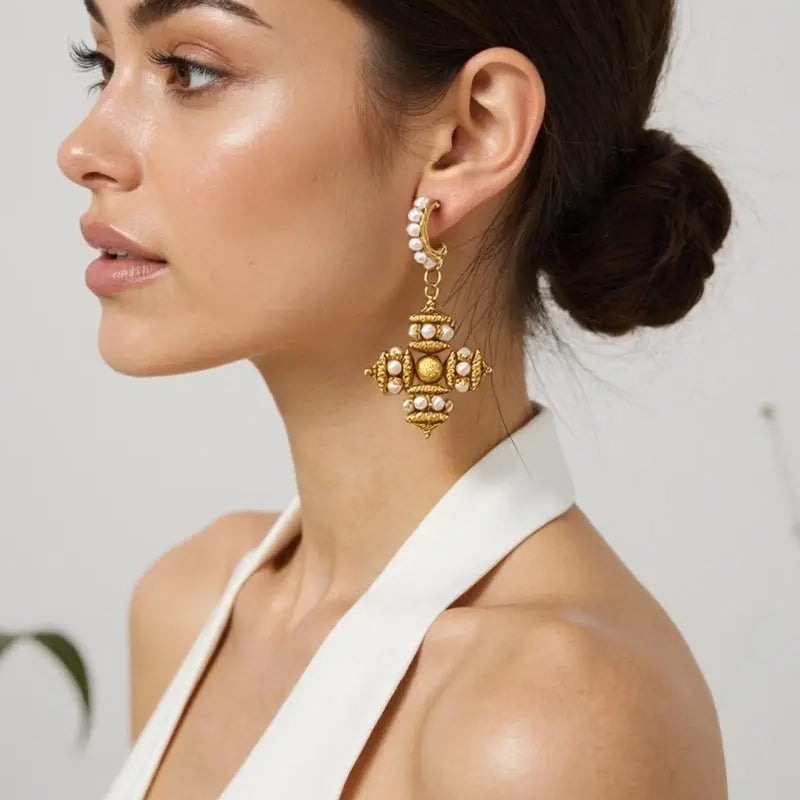 Model wearing Opulence gold filigree drop earrings with faux pearl accents