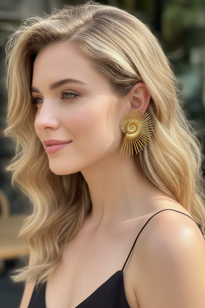 Close-up of a model showcasing sculptural 18K gold plated Nautilus Spiral earrings. These bold statement studs elevate a minimalist black outfit with artistic, architectural flair.