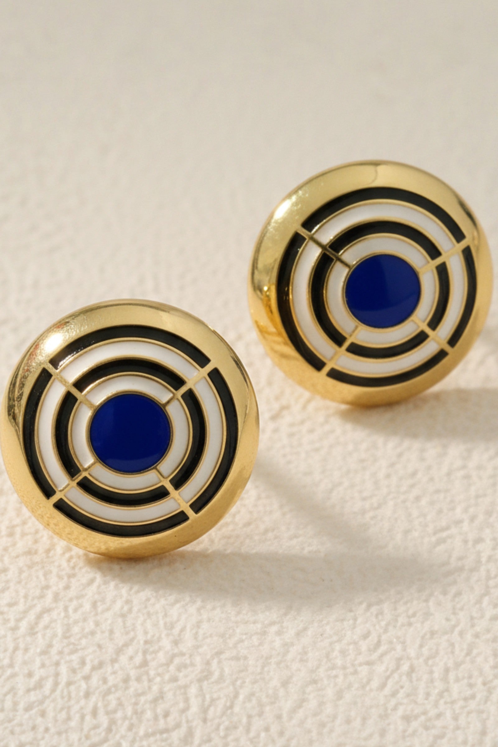 Large cobalt blue and white enamel concentric circle dôme earrings, showing oversized fit and high-shine finish.