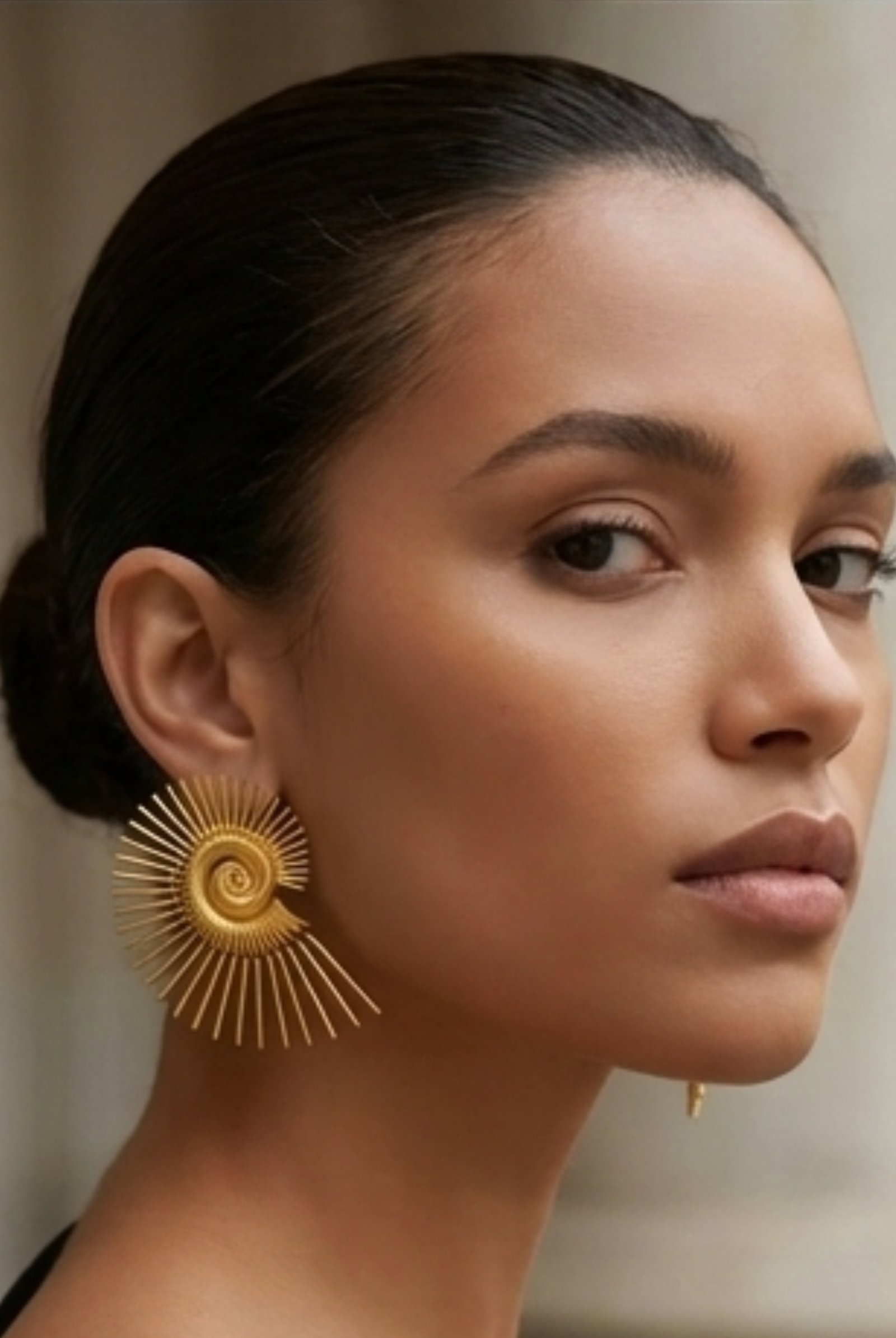 Large golden spiral wire earrings with a nautilus-inspired geometric design, showcasing the oversized architectural silhouette.