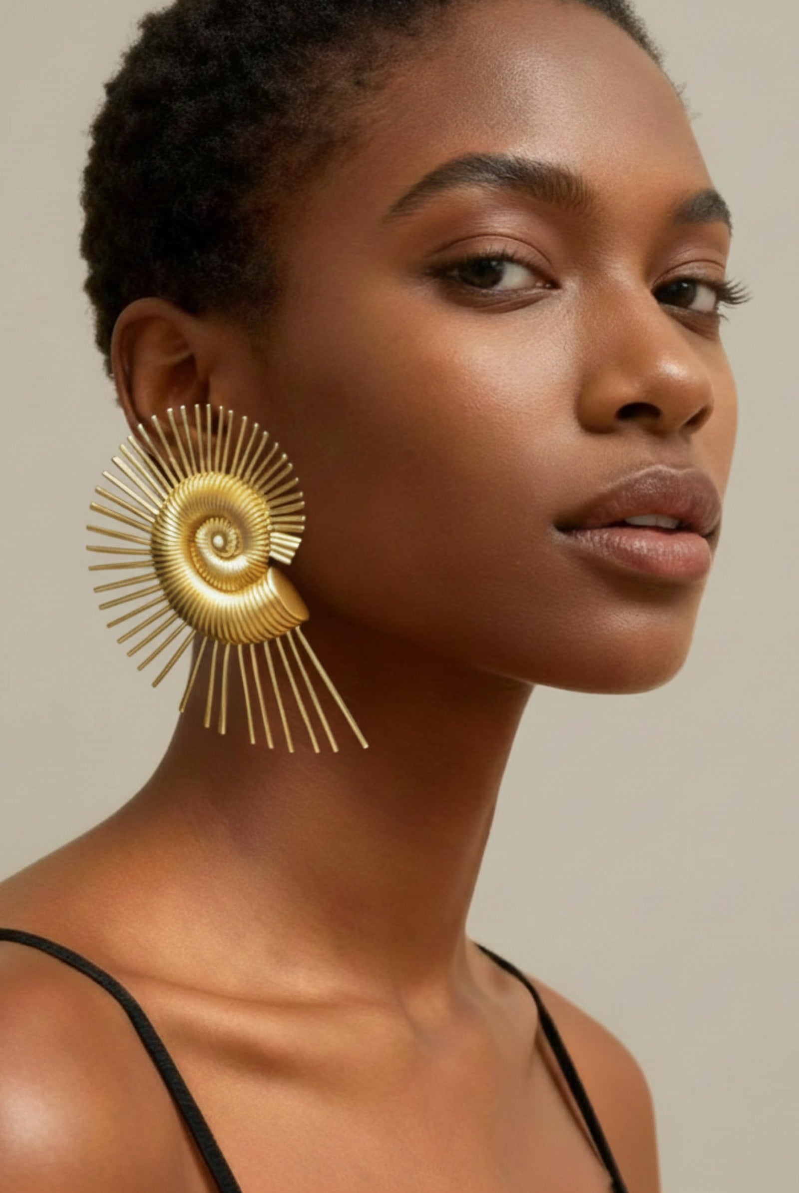 Large golden spiral wire earrings with a nautilus-inspired geometric design earrings on a model, showing oversized fit and high-shine finish.