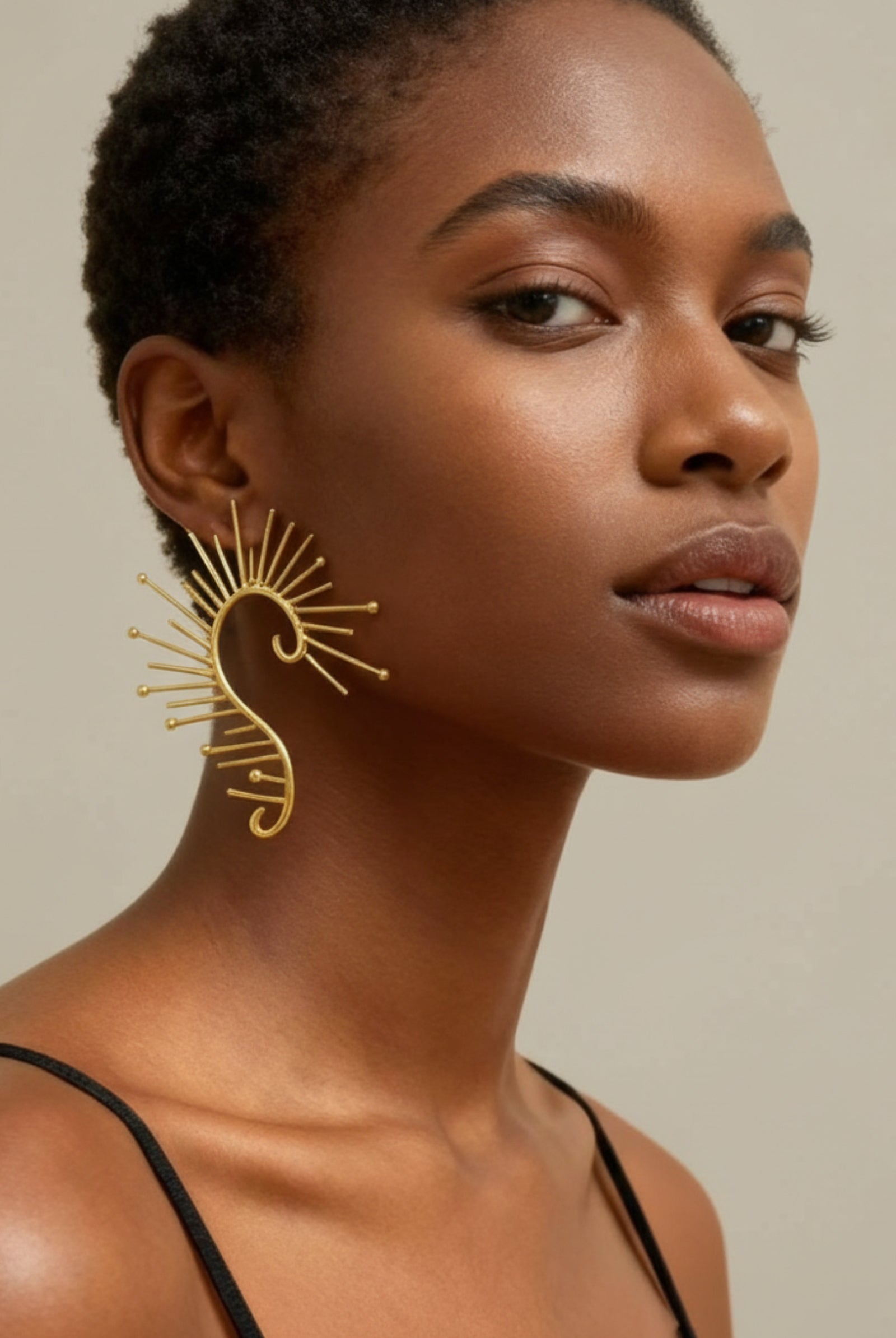 Large gold sunburst statement earrings on model, celestial festival jewelry ear cuff style, fashion earrings for women.