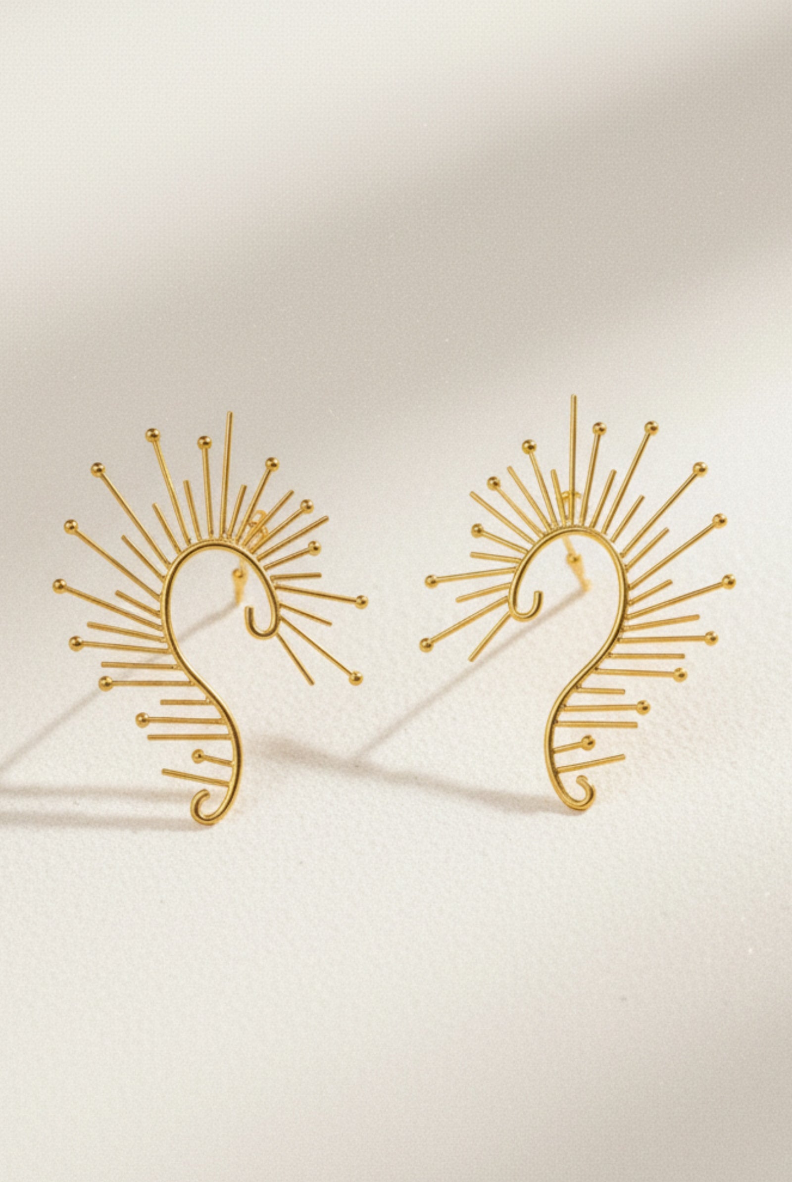 18K gold plated sunburst ear crawlers featuring delicate wire rays, styled as a statement sculptural ear climber.