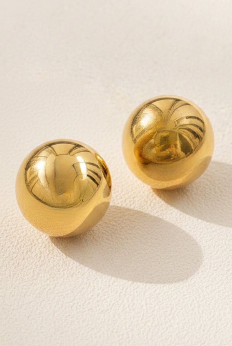 Close-up shot of the Aura Sculpted Dome Studs on a soft beige background, highlighting the smooth texture of these lightweight hollow gold ball studs, popular in US and European boutique indie designer jewelry trends.