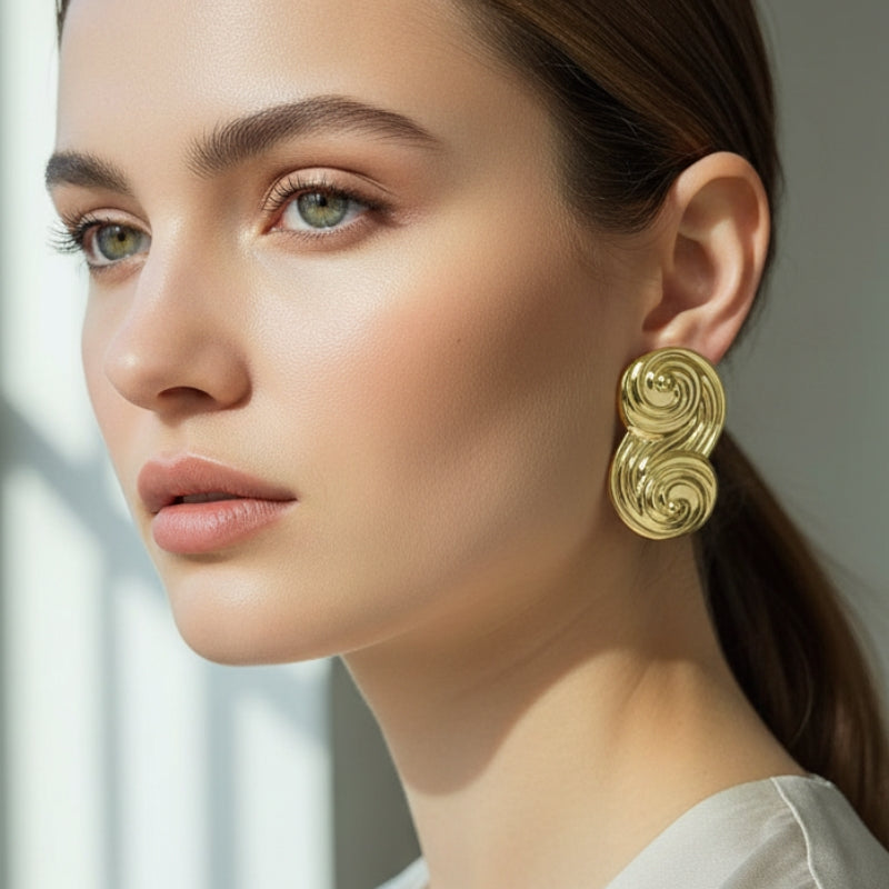 Side profile of model wearing gold Seraphina sculptural swirl stud earrings