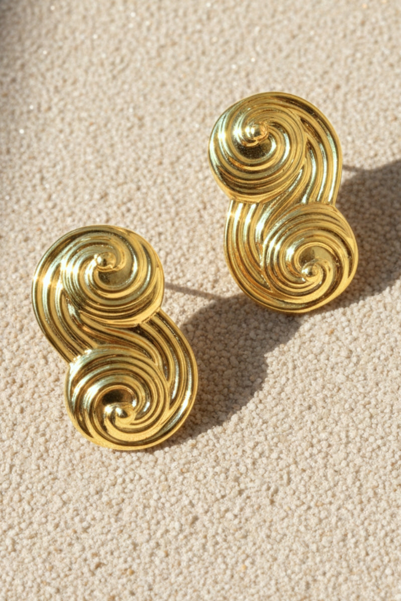 Detailed shot of liquid gold-effect infinity earrings highlighting the fluid curves.