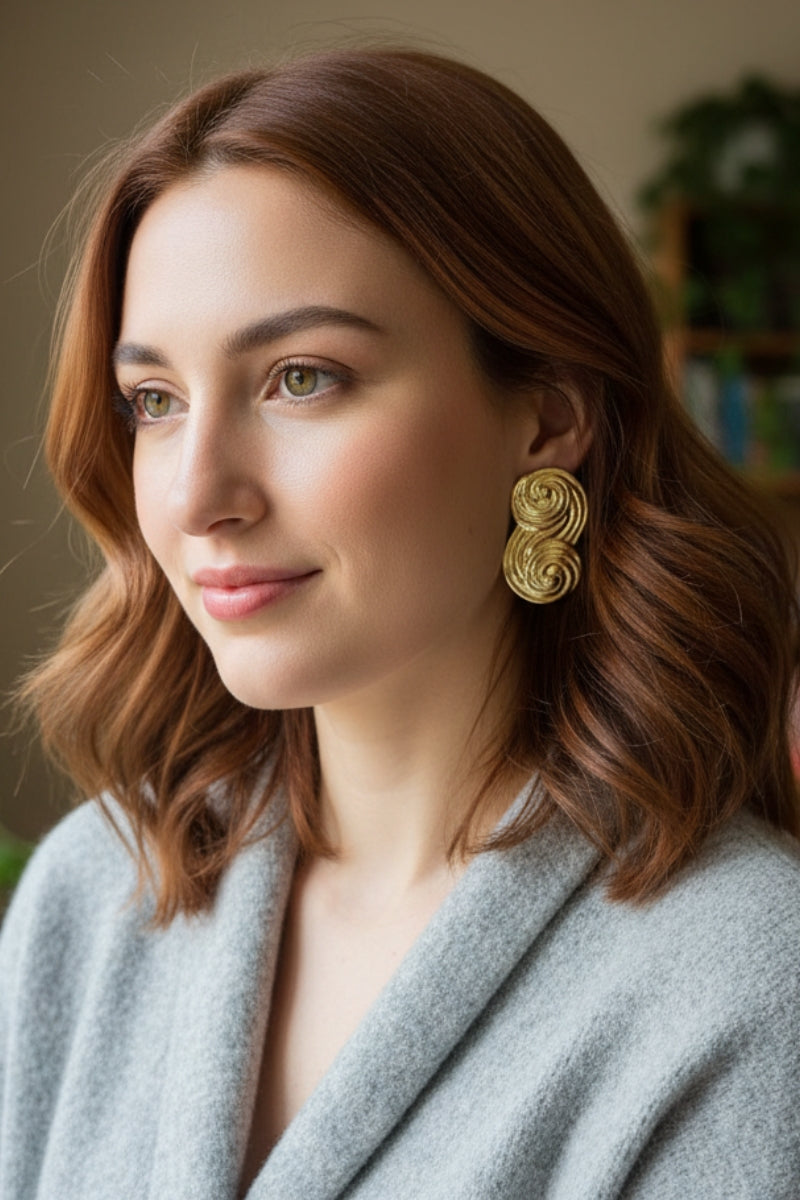 Seraphina gold statement earrings worn with casual grey knitwear, versatile everyday luxury jewelry for London boutiques.