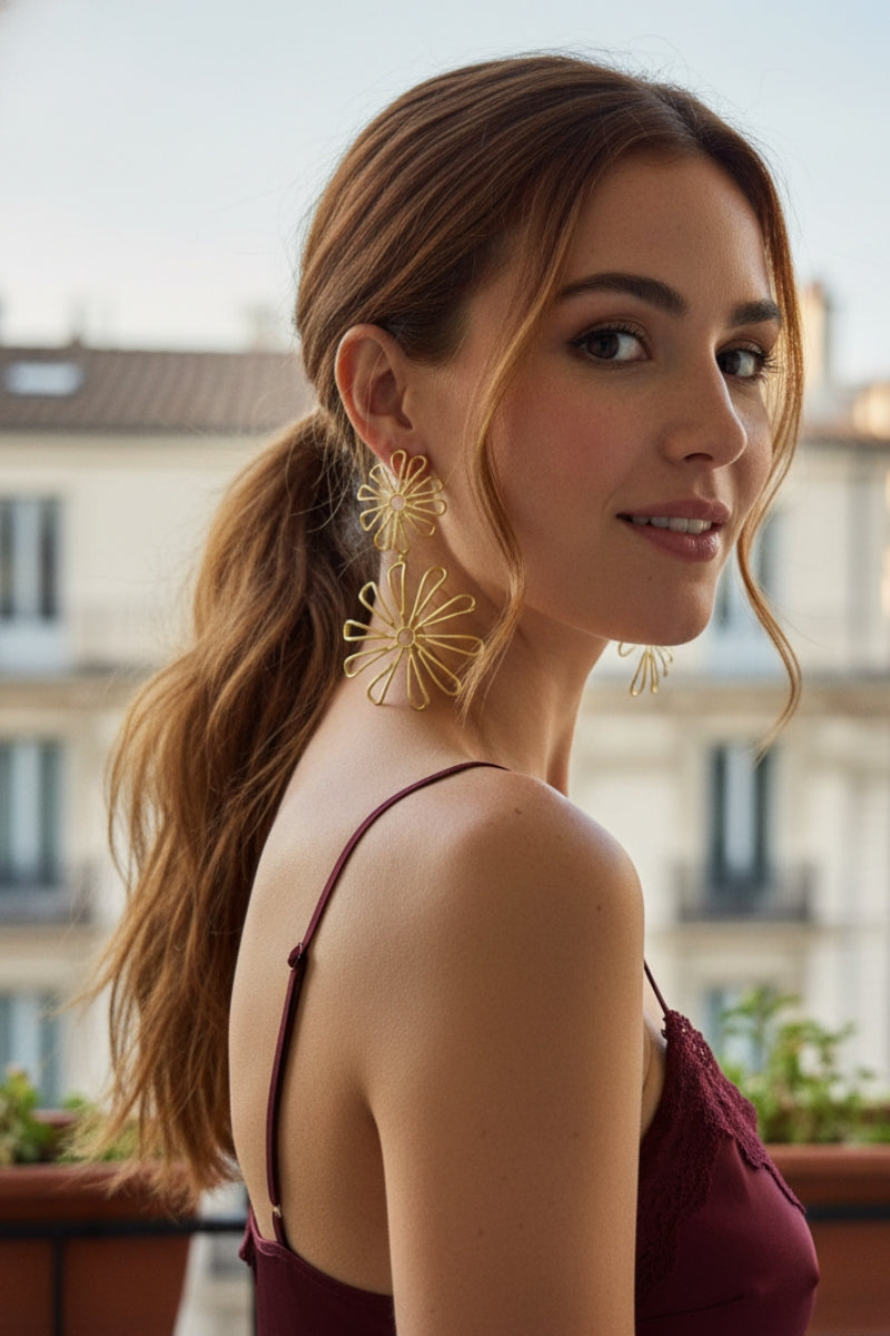 Smiling model wearing gold floral statement dangles at a garden party, perfect for UK spring and summer accessories.