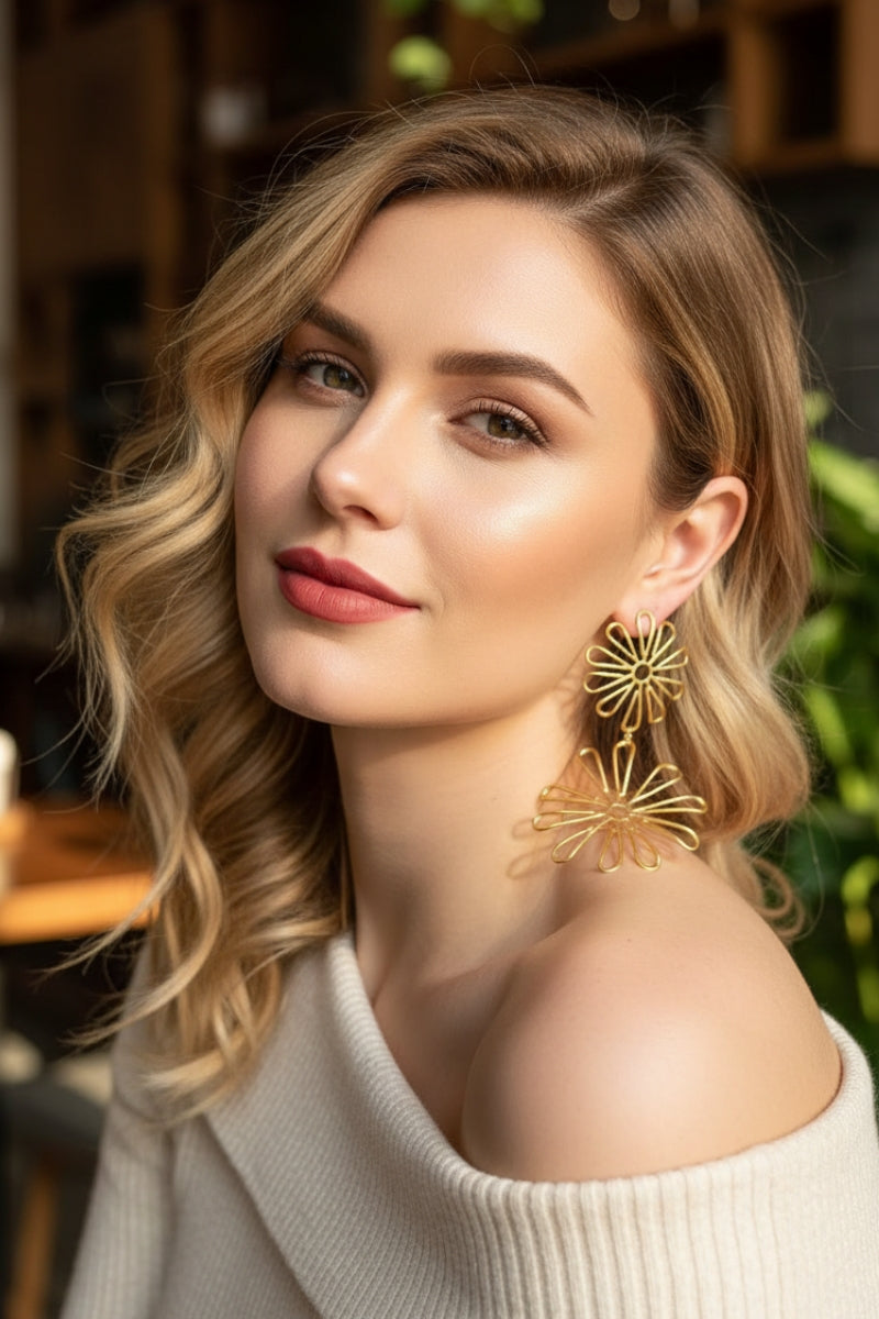 Boho style gold flower drop earrings styled with an off-the-shoulder cream sweater, chic autumn fashion jewelry for Paris boutiques.