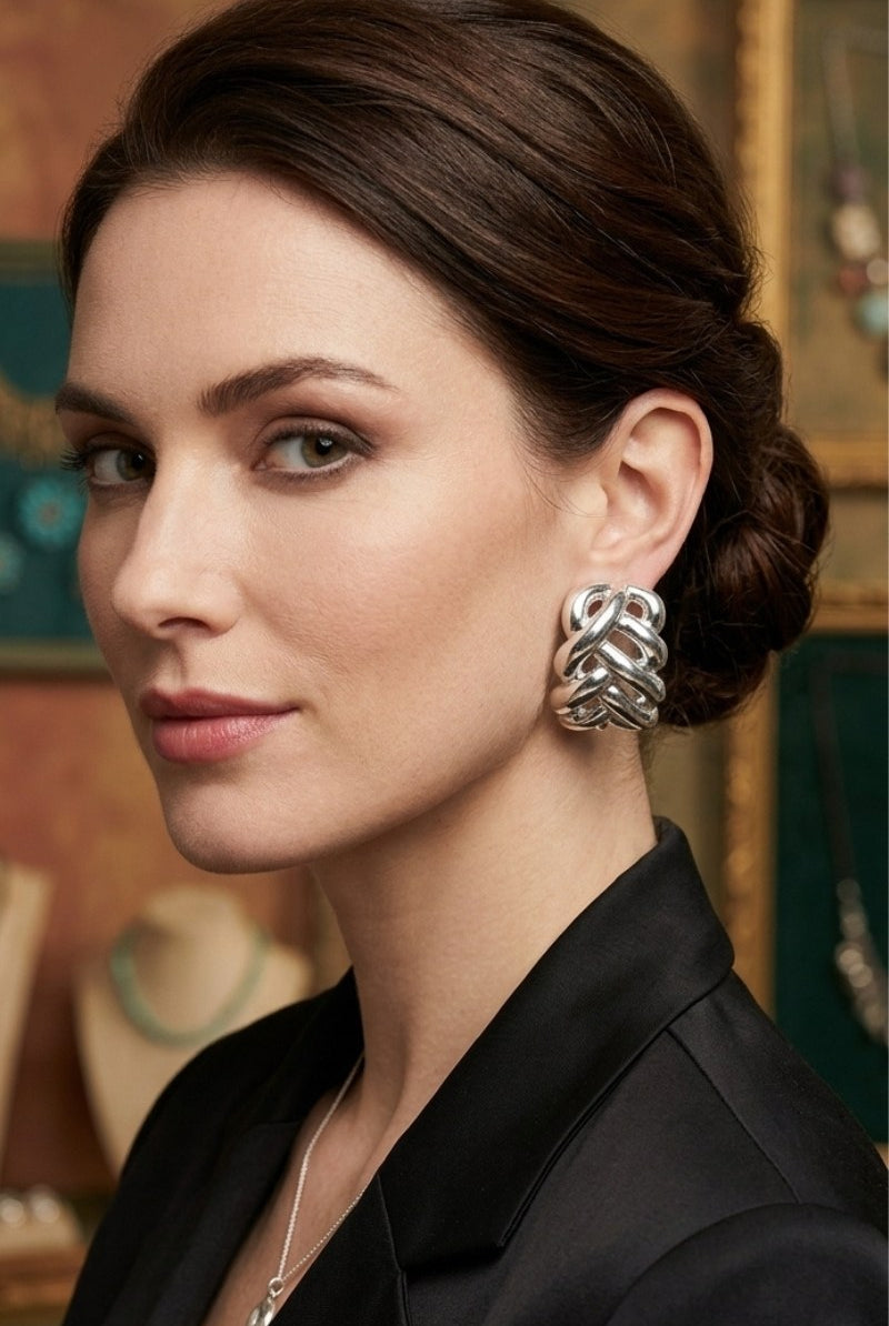 Model wearing silver-tone braided half-hoop earrings with a black blazer