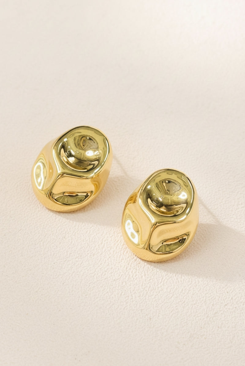 Pair of Isla molten gold statement earrings with a high-shine reflective surface and unique sculptural design on a neutral background.