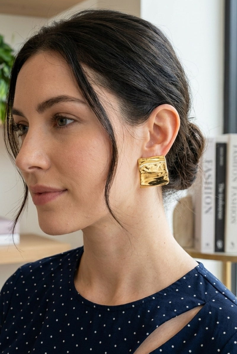 Model wearing crinkled gold square statement studs, view 2