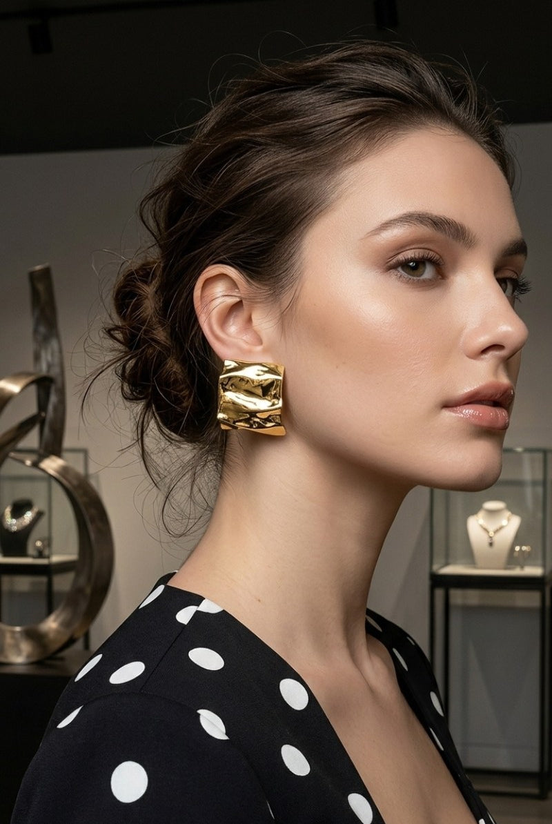 Model wearing crinkled gold square statement studs, view 3