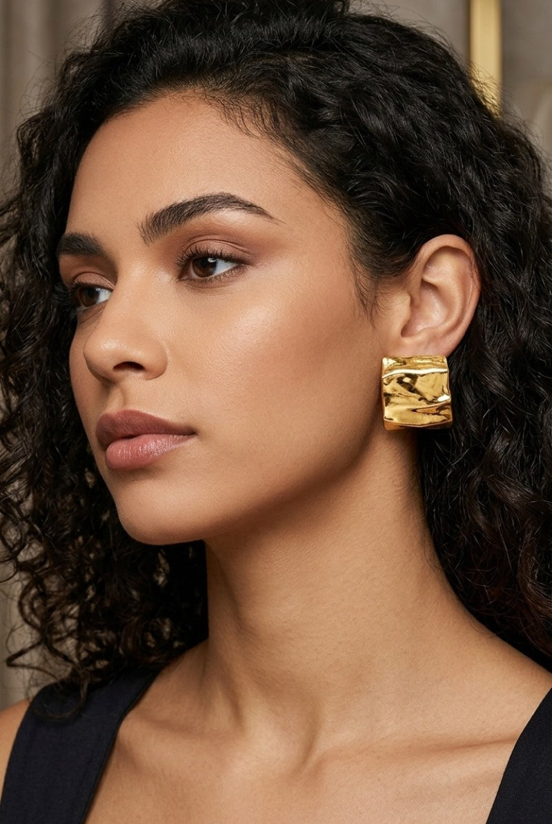 Model wearing crinkled gold square statement studs, view 4