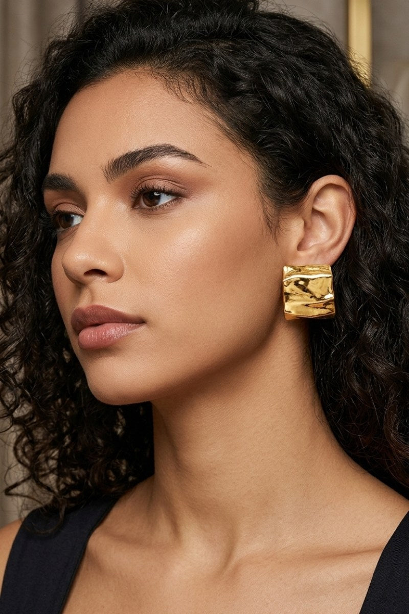 Model wearing crinkled gold square statement studs, view 4