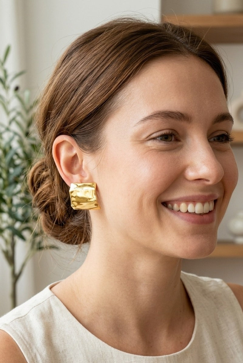 Model wearing crinkled gold square statement studs, view 6