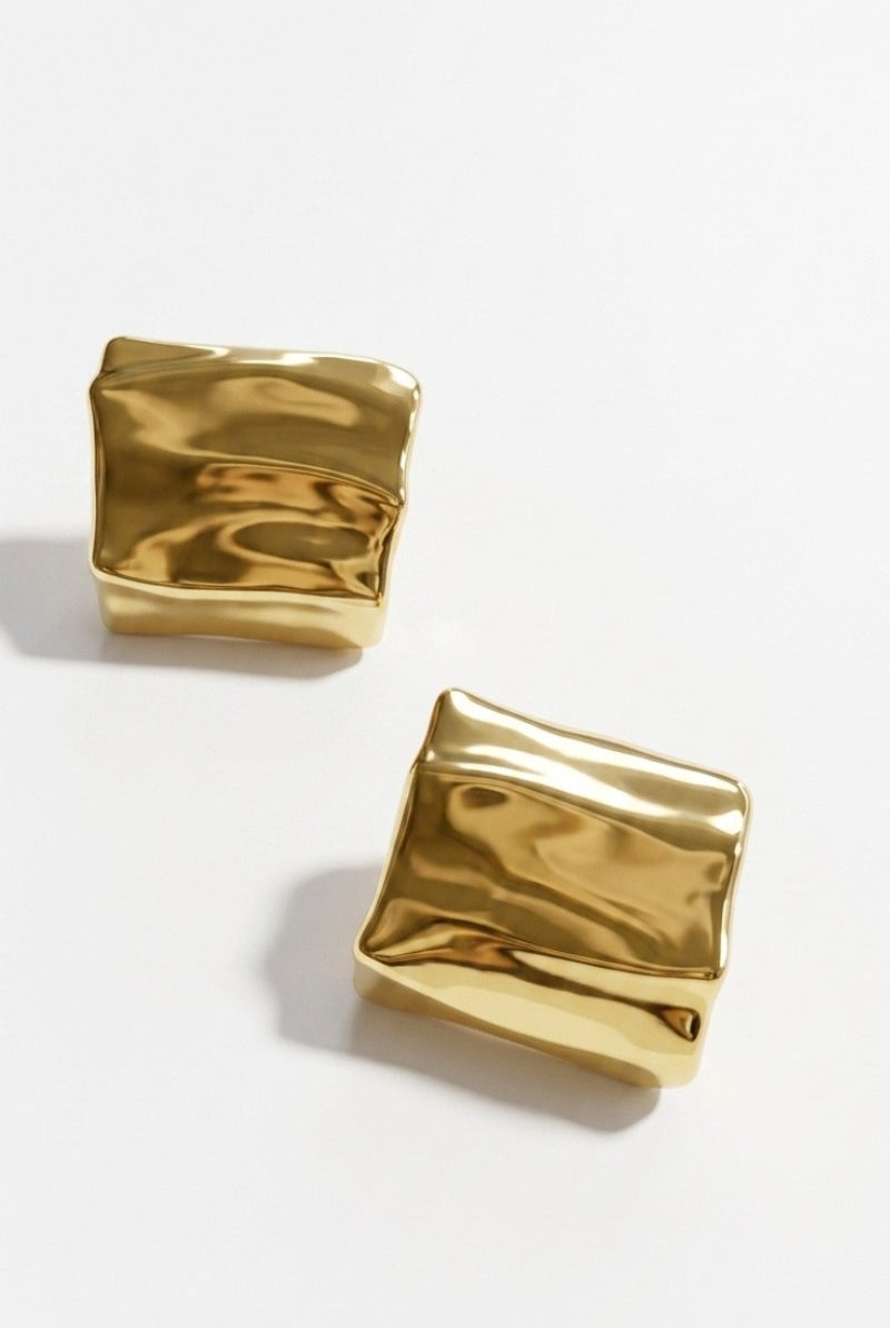 Pair of crinkled gold square statement studs on a white background