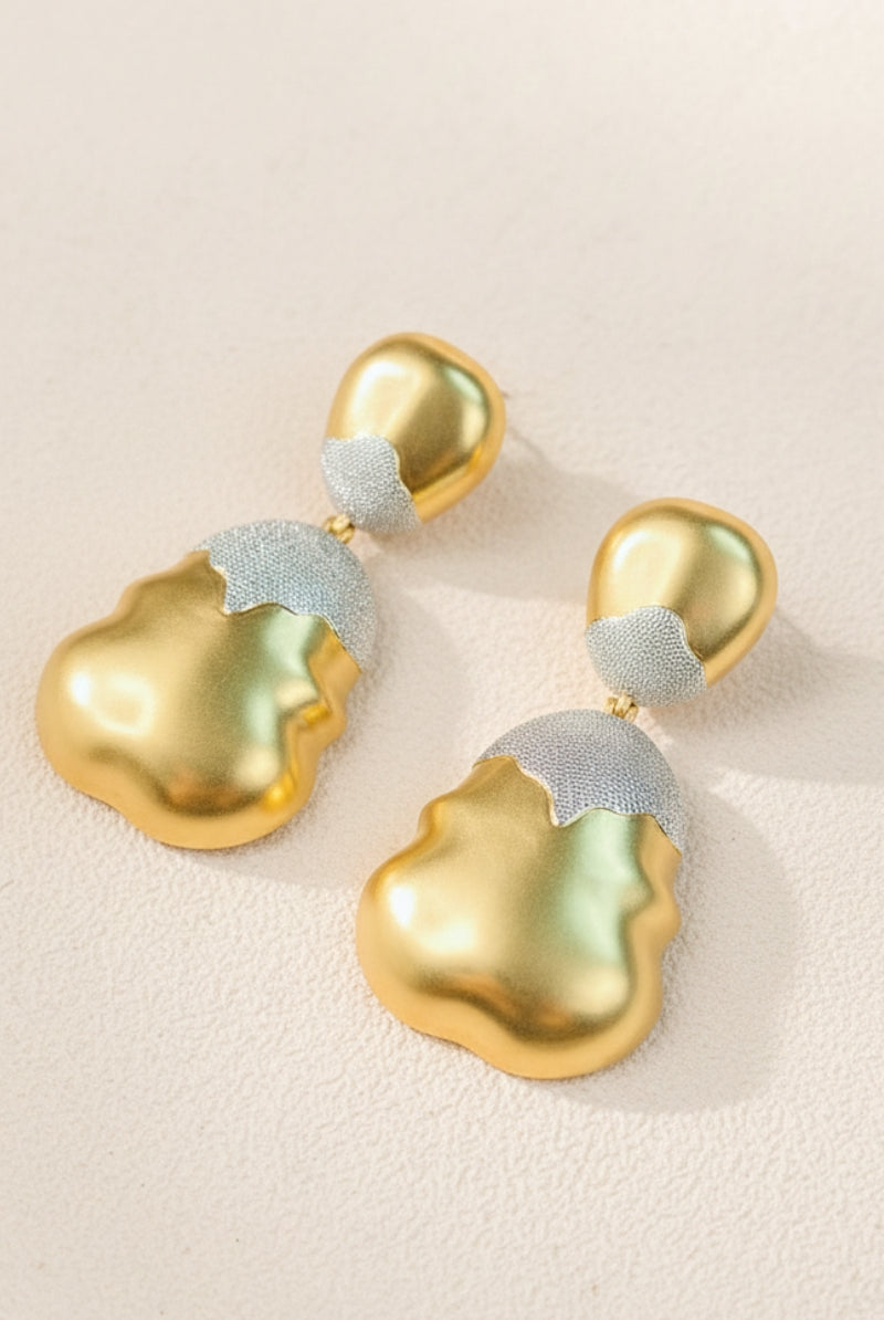 High-detail view of Luna mixed metal earrings with a shimmering frosted silver top and wavy molten gold bottom.