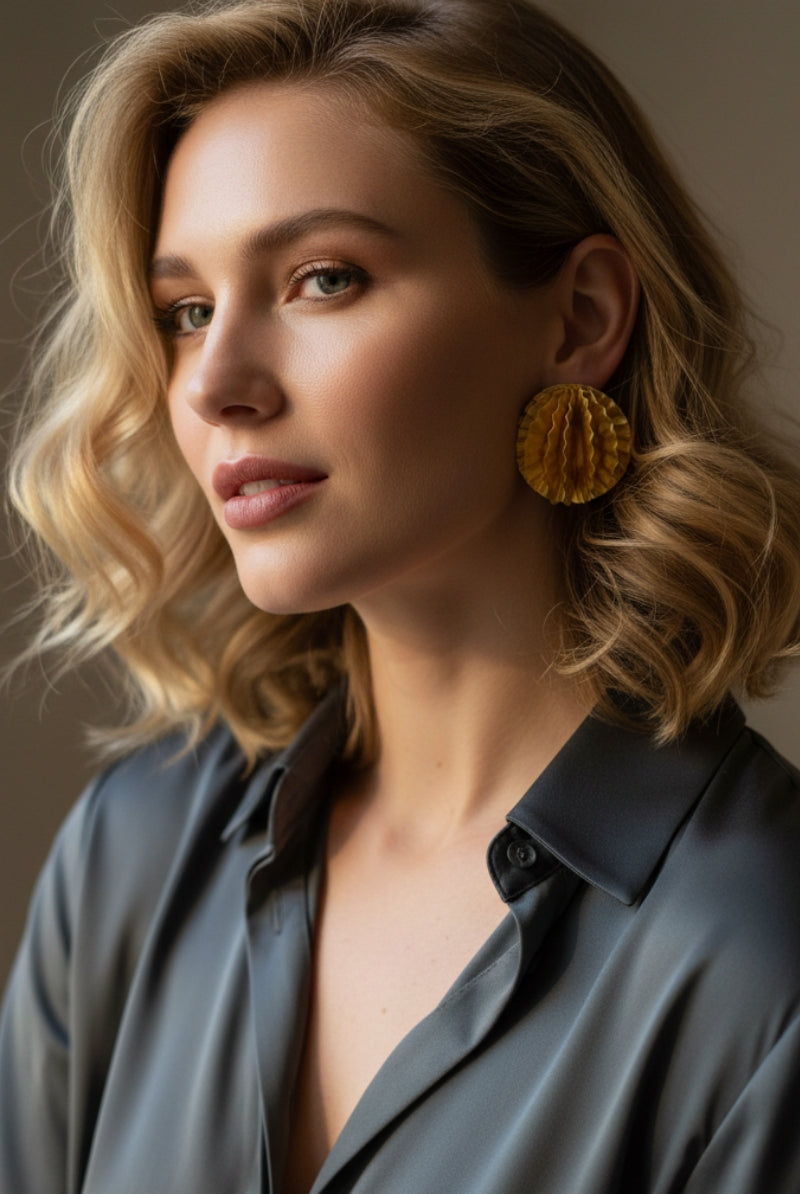 Aurelia honeycomb textured gold studs paired with a professional grey silk blouse, modern office wear jewelry trends for European fashion boutiques.