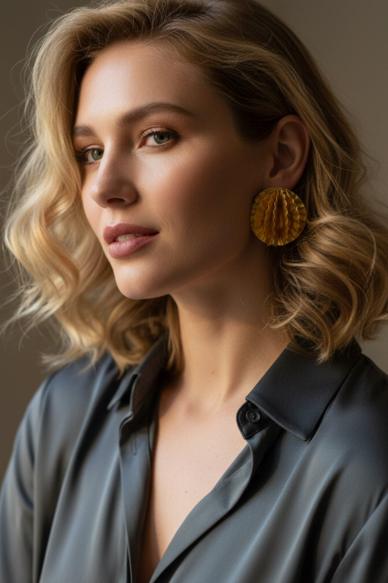 Aurelia honeycomb textured gold studs paired with a professional grey silk blouse, modern office wear jewelry trends for European fashion boutiques.