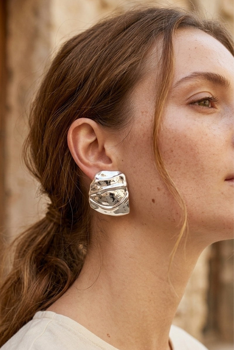 Model wearing liquid silver square statement stud earrings, view 1