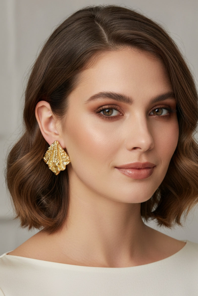A high-fashion shot featuring the Mirage Earrings, an 18k gold-plated statement piece with an artisanal textured aesthetic.