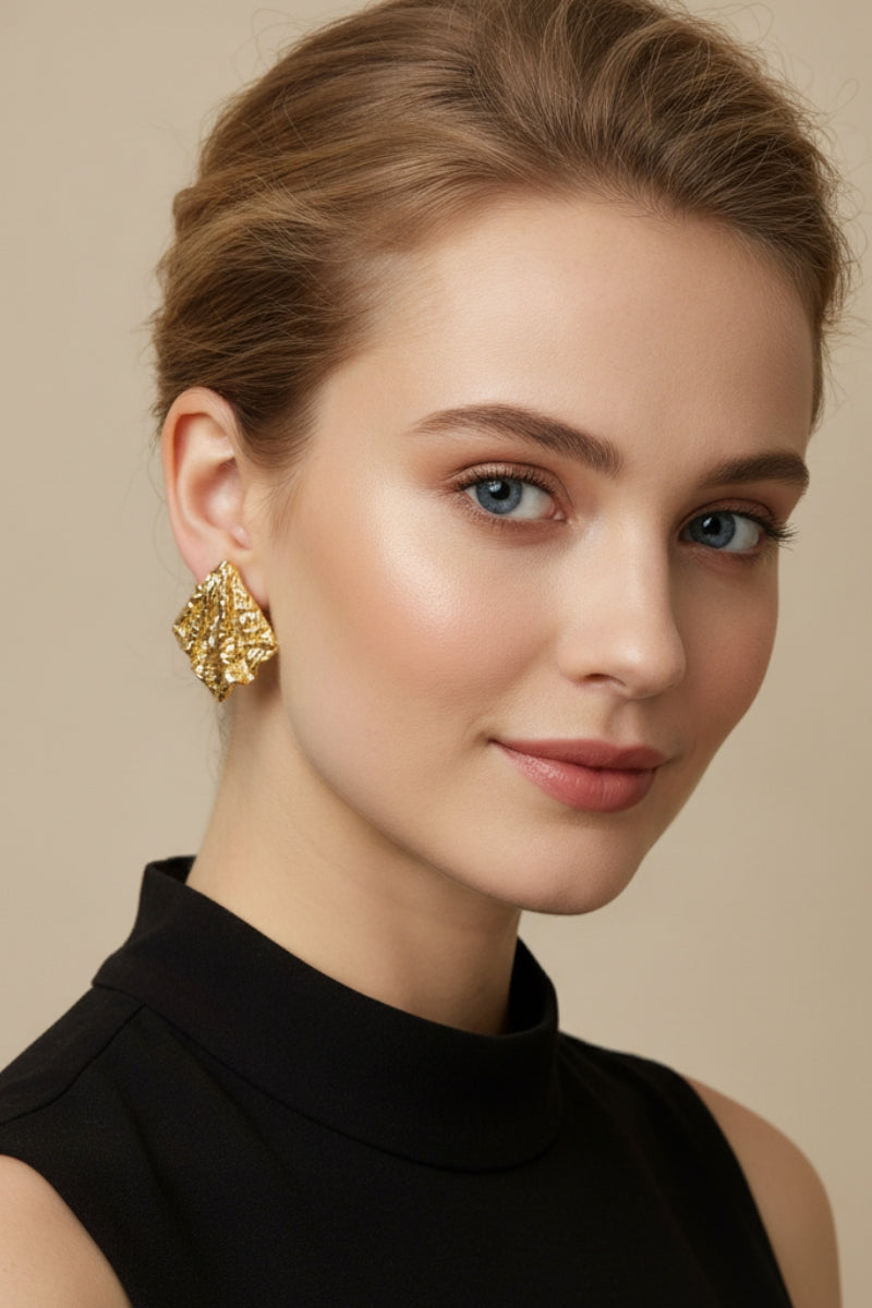 A model styling the Mirage Earrings, highlighting the sculptural gold form that brings a touch of modern minimalist chic.