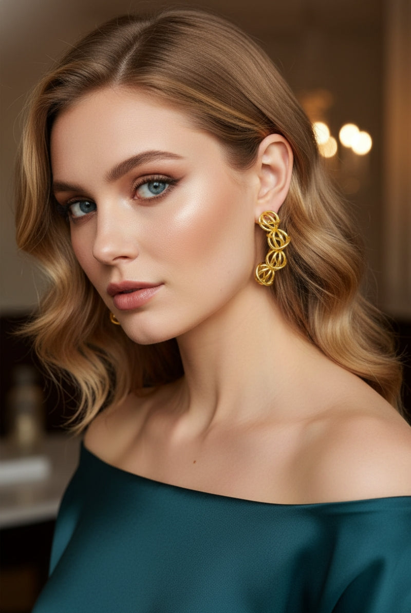 A close-up portrait of a blonde woman in an off-the-shoulder emerald satin gown. She wears the dramatic 5-sphere curved drop earrings, capturing a classic old-money aesthetic perfect for gala dinners or formal guest styling.