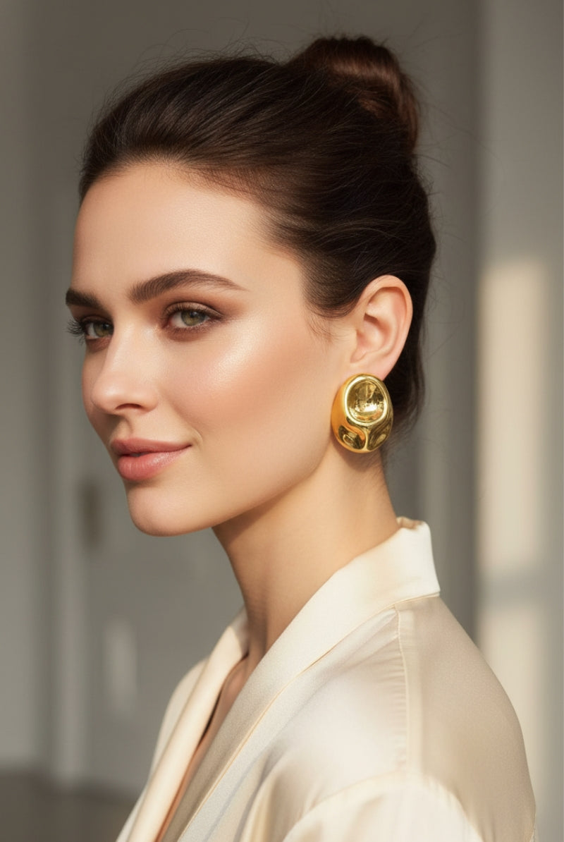 Elegant model wearing large irregular liquid gold earrings, highlighting high-shine reflective finish and mob wife aesthetic.