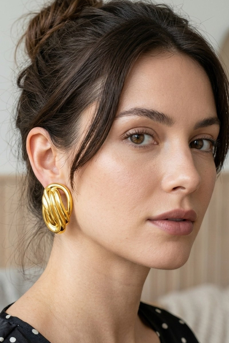 Model wearing sculptural oval knot statement stud earrings, view 1