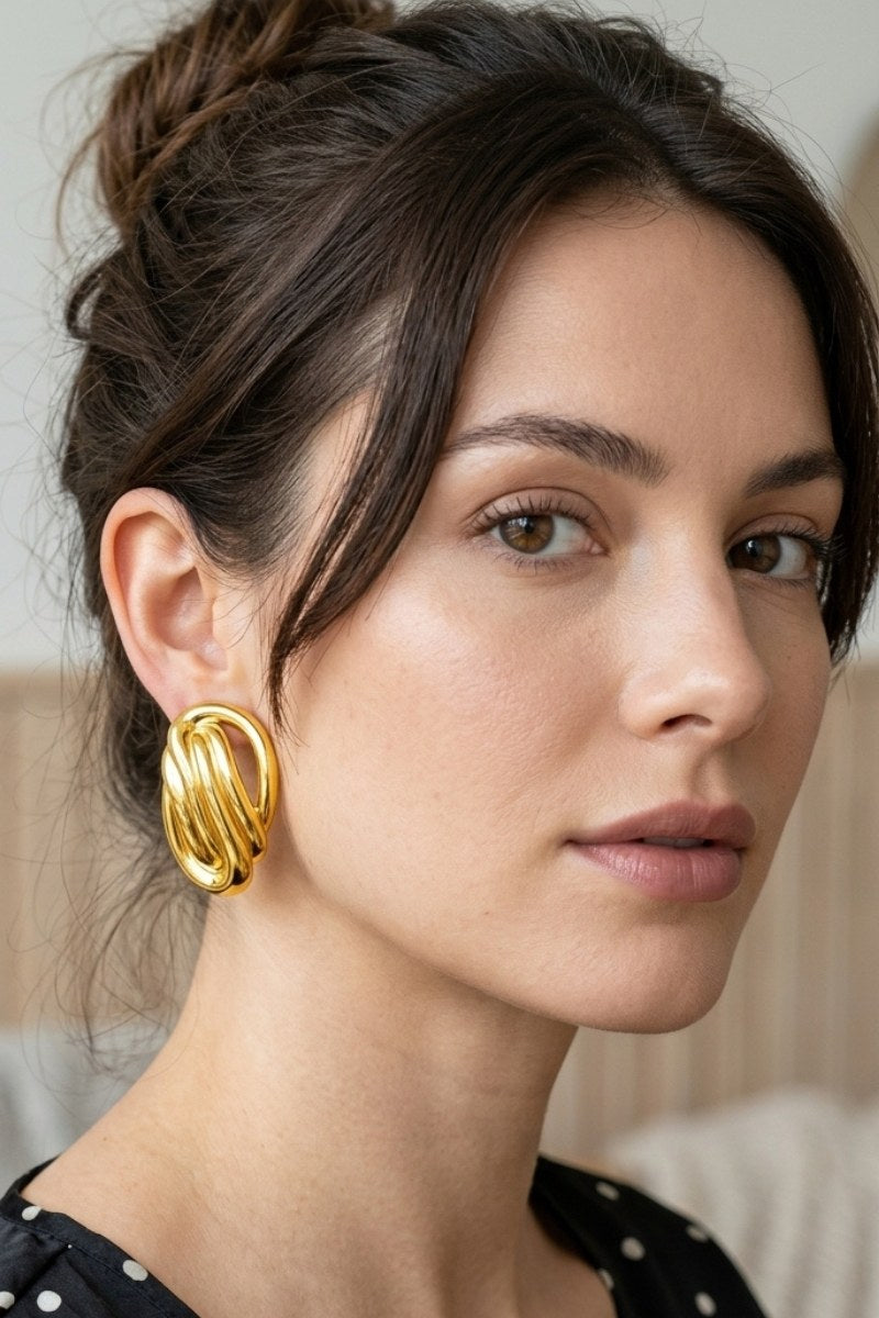 Model wearing sculptural oval knot statement stud earrings, view 1