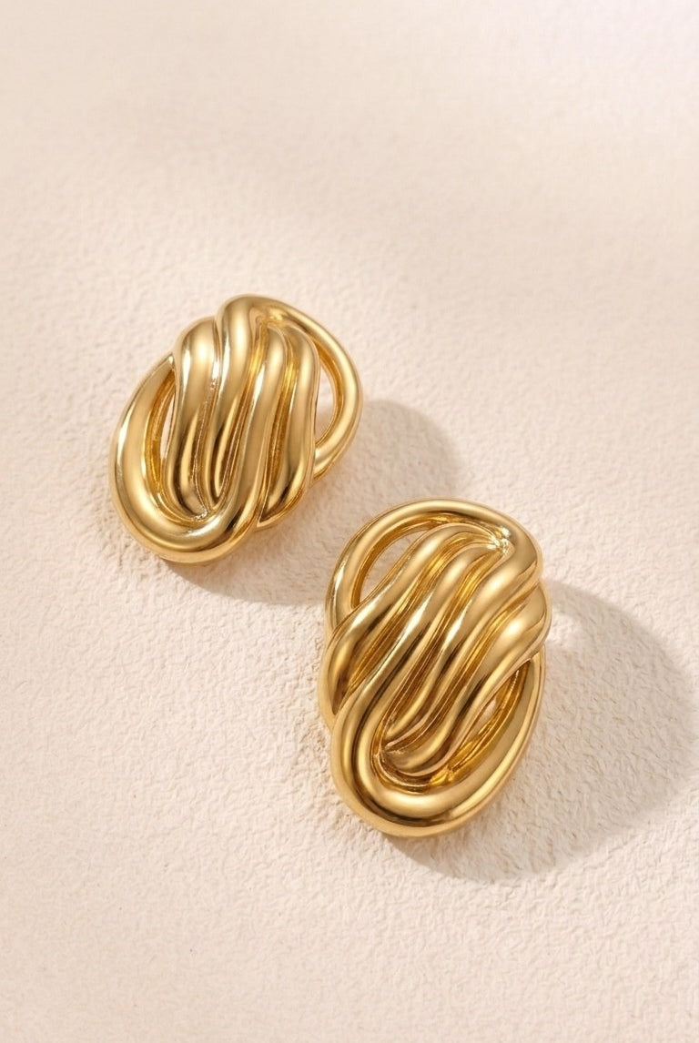 Pair of sculptural oval knot statement stud earrings on a white background