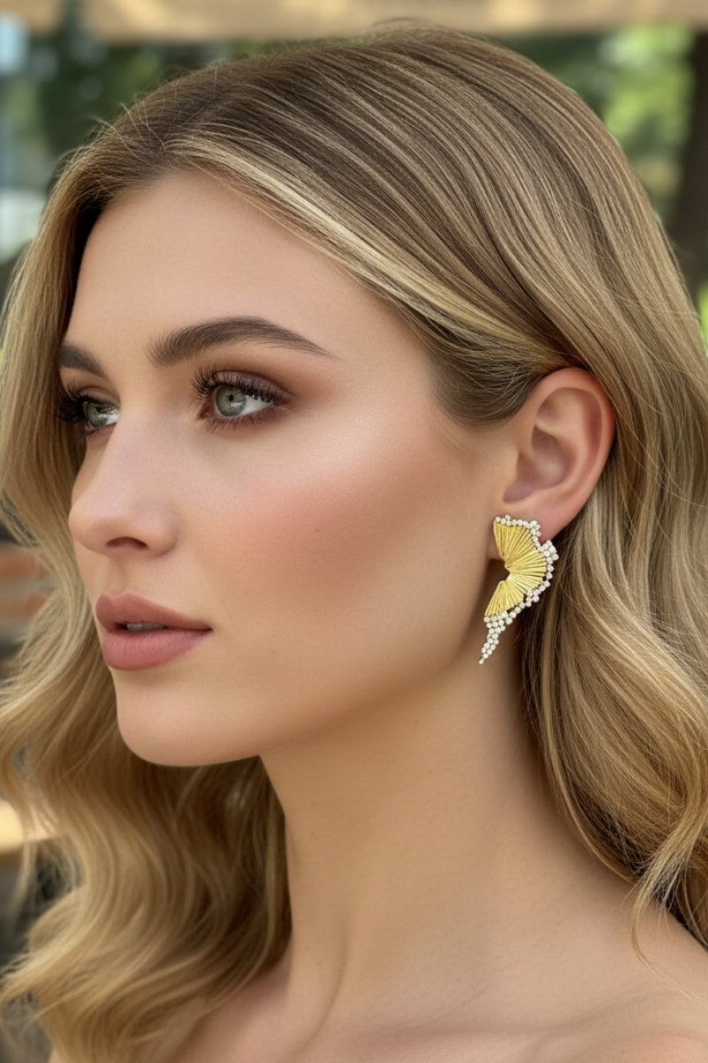 Sculptural gold wing earrings featuring micro-pearl inlay and artisan pleats in Milan.