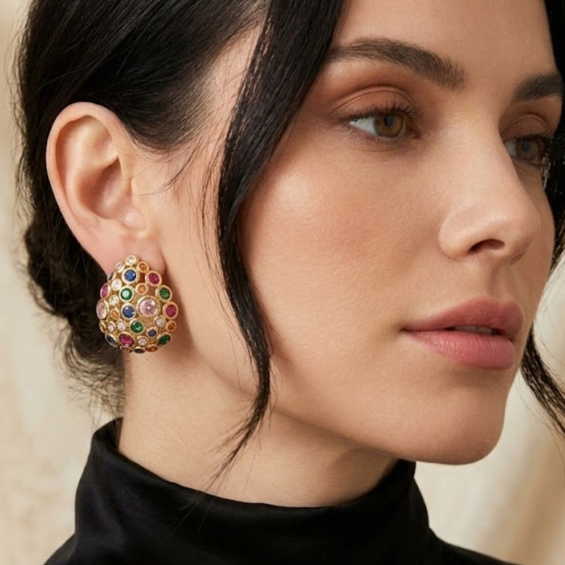 Professional portrait of a woman showcasing Starlight Oval Earrings featuring an intricate cluster of multi-colored stones set in 18K gold plated brass.