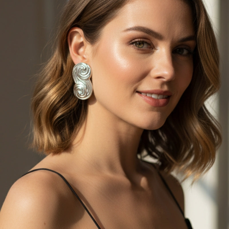 Model wearing white-gold-plated Seraphina sculptural swirl stud earrings