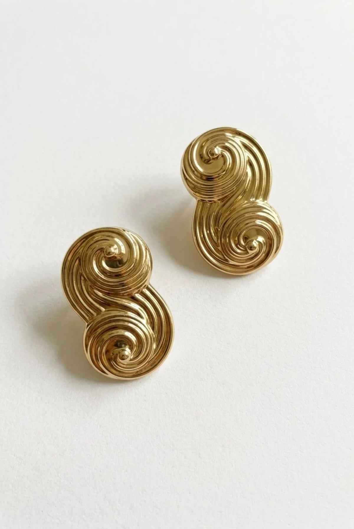 Seraphina Small gold-plated sculptural stud earrings with polished double-swirl detailing, displayed as a pair on a white background.