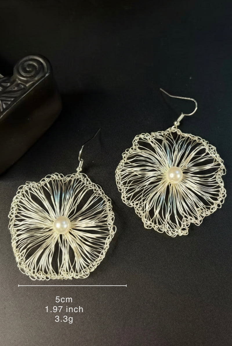 Detail view of large silver-toned hand-crocheted wire filigree drops, a perfect tarnish-resistant statement piece for a minimalist evening look.