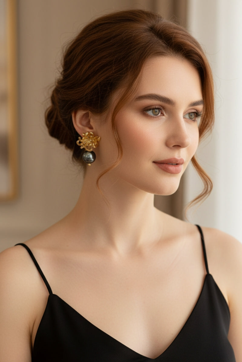 Soft cinematic photography of an auburn-haired woman wearing organic metalwork romantic drops with gold botanical petals and a high-luster black pearl, showcasing high-end independent fashion jewelry design.