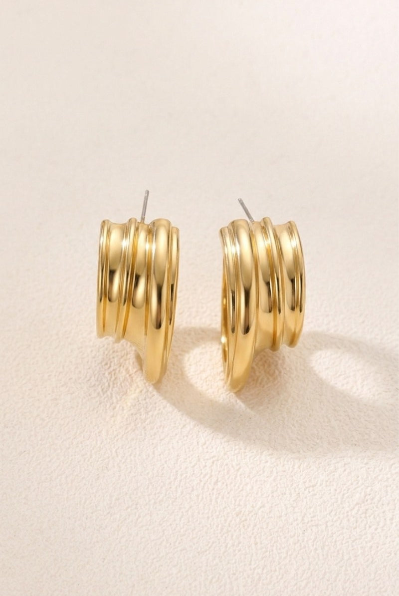 Triple-ribbed wave hoop earrings on a warm beige background