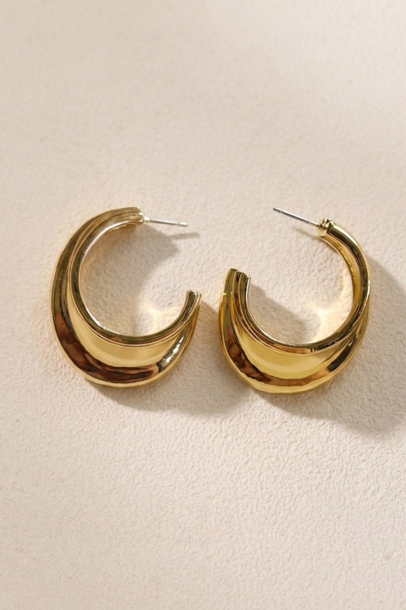 Side detail of triple-ribbed wave hoop earrings showing the earring profile and posts