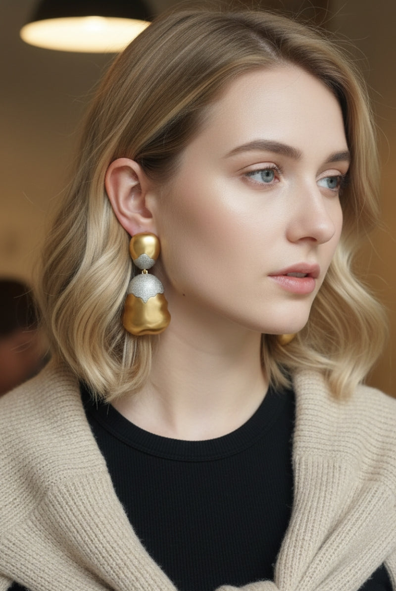 Close-up of model wearing organic shaped mixed metal earrings with casual chic knitwear, highlighting the gold and silver contrast.