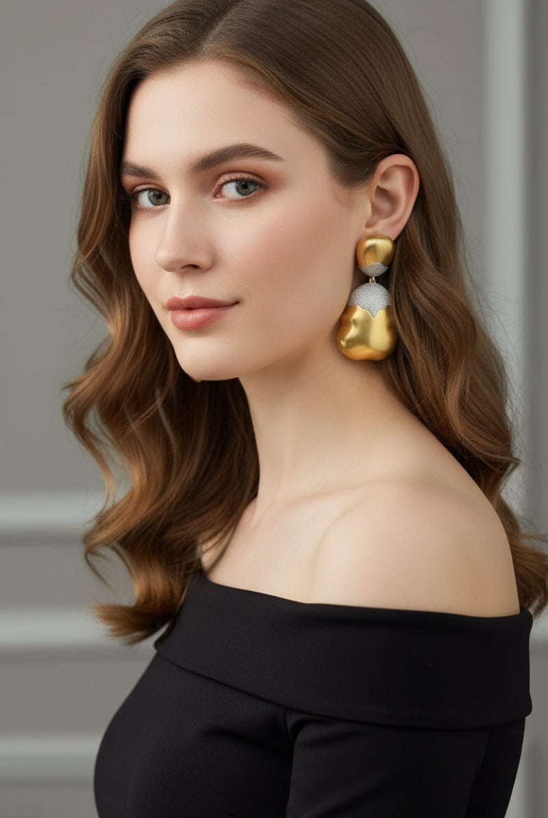 Elegant updo hairstyle showcasing oversized gold and silver mixed metal drop earrings, perfect for wedding guests or black-tie events.