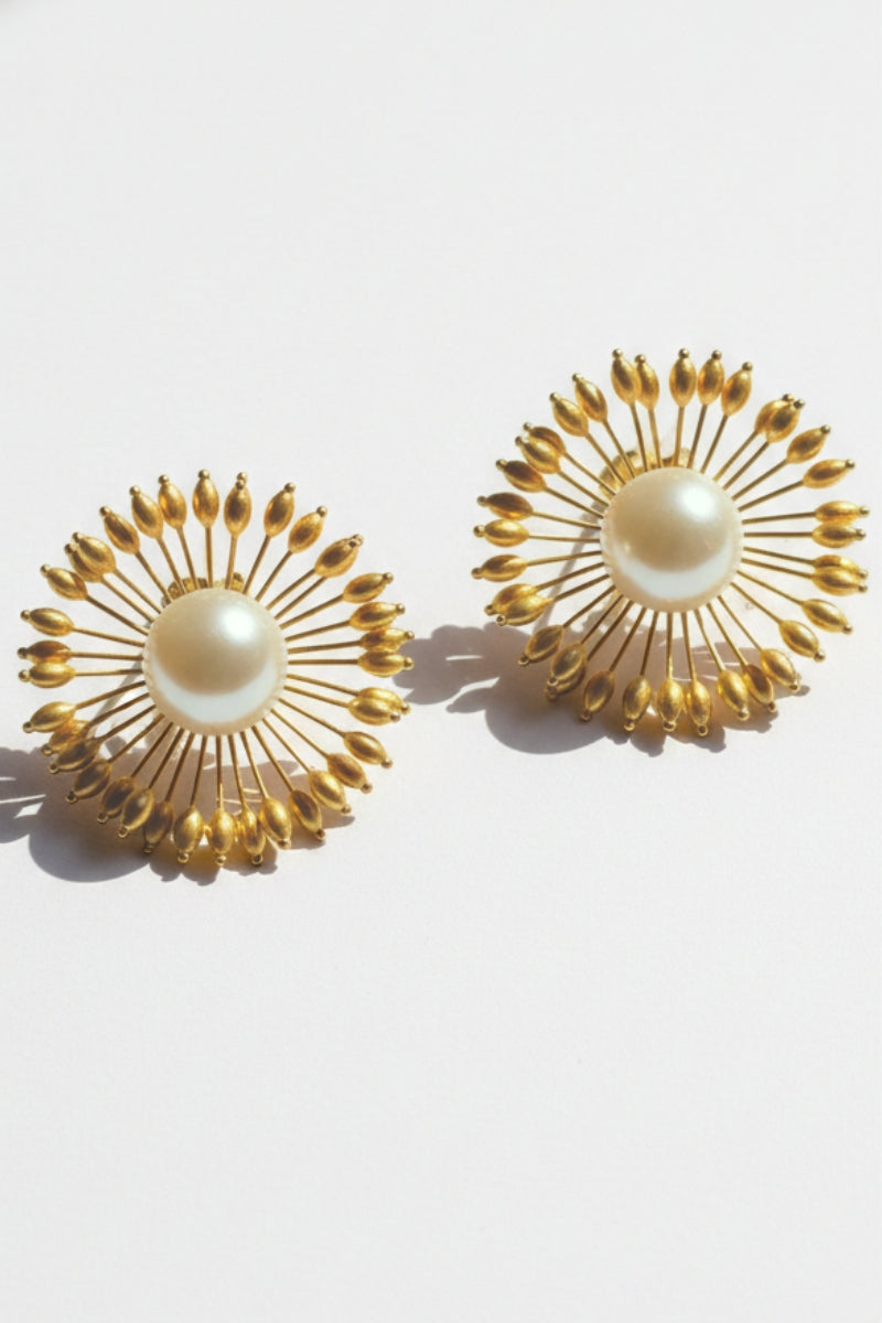 Close-up of a lustrous baroque pearl surrounded by gold sunrays, showcasing the high-quality vintage revival craftsmanship.