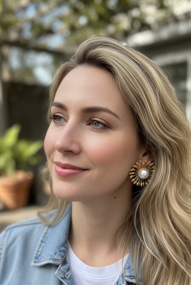Woman wearing Hera 18K gold sunburst pearl earrings with denim jacket, casual chic daily jewelry style for women in North America.