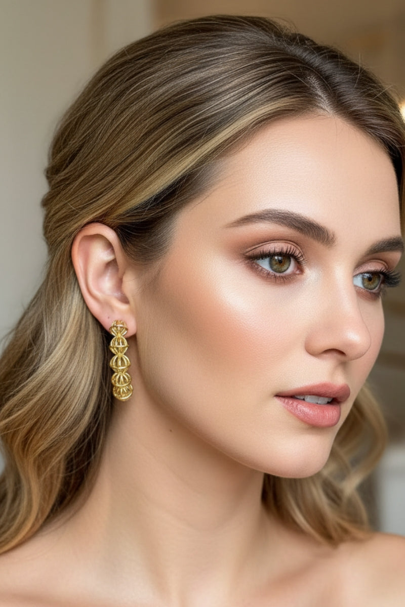 A side angle of a woman with a chic half-up hairstyle showcasing the vintage-inspired hollow ball drop earrings, perfectly paired for formal events, holiday parties, or elegant wedding guest styling.