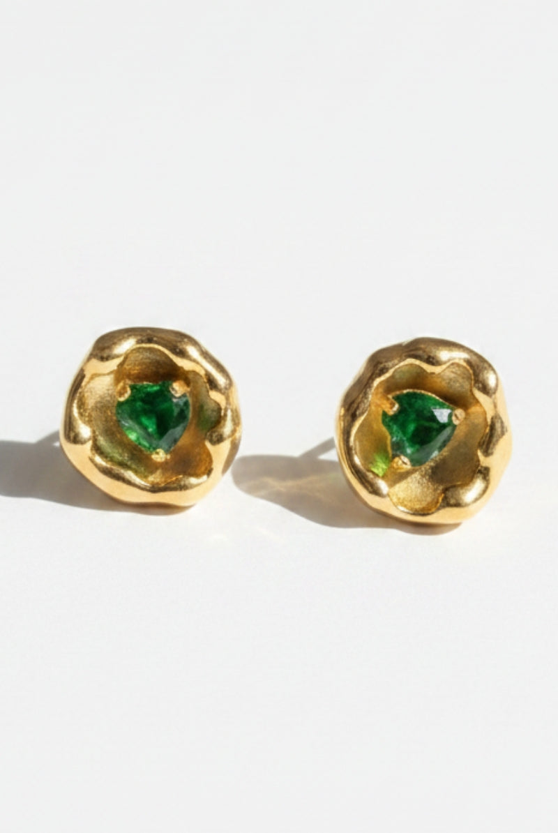Vintage-inspired organic metal stud earrings featuring vibrant heart-shaped green crystal stones in molten gold frames, displaying nickel-free hypoallergenic sterling silver posts for sensitive ears.